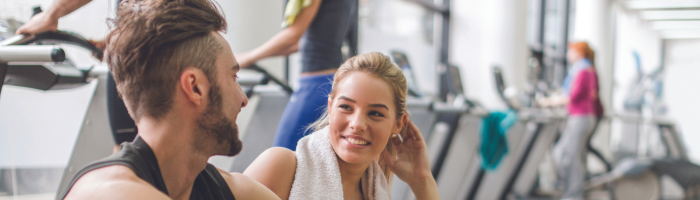 Man and woman smiling at each other in gym